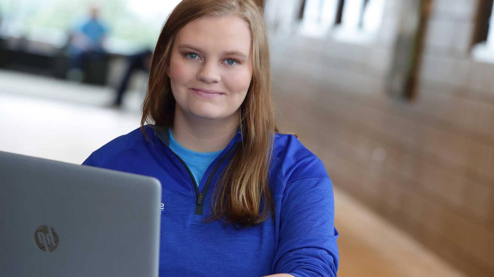 Female student working on laptop, smiling